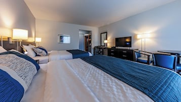 Une chambre d’hôtel avec un grand lit, un bureau, une chaise, une télévision et une armoire.