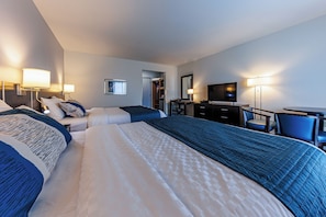 Una habitación de hotel con una cama grande, un escritorio, una silla, un televisor y un armario.
