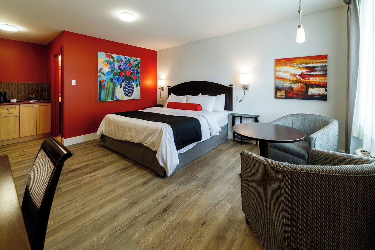 Ein Hotelzimmer mit einem Bett, einem Esstisch, einem Stuhl, einem kleinen Tisch und einem Bild an der Wand.