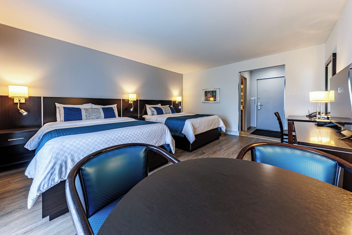 Ein Hotelzimmer mit zwei Betten, einem Esstisch und einem Fernseher.
