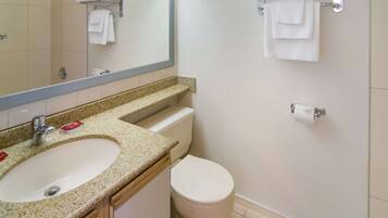 Un baño con lavamanos, inodoro y toalleros.