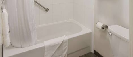 A bathroom with a bathtub, toilet, and a shower curtain.