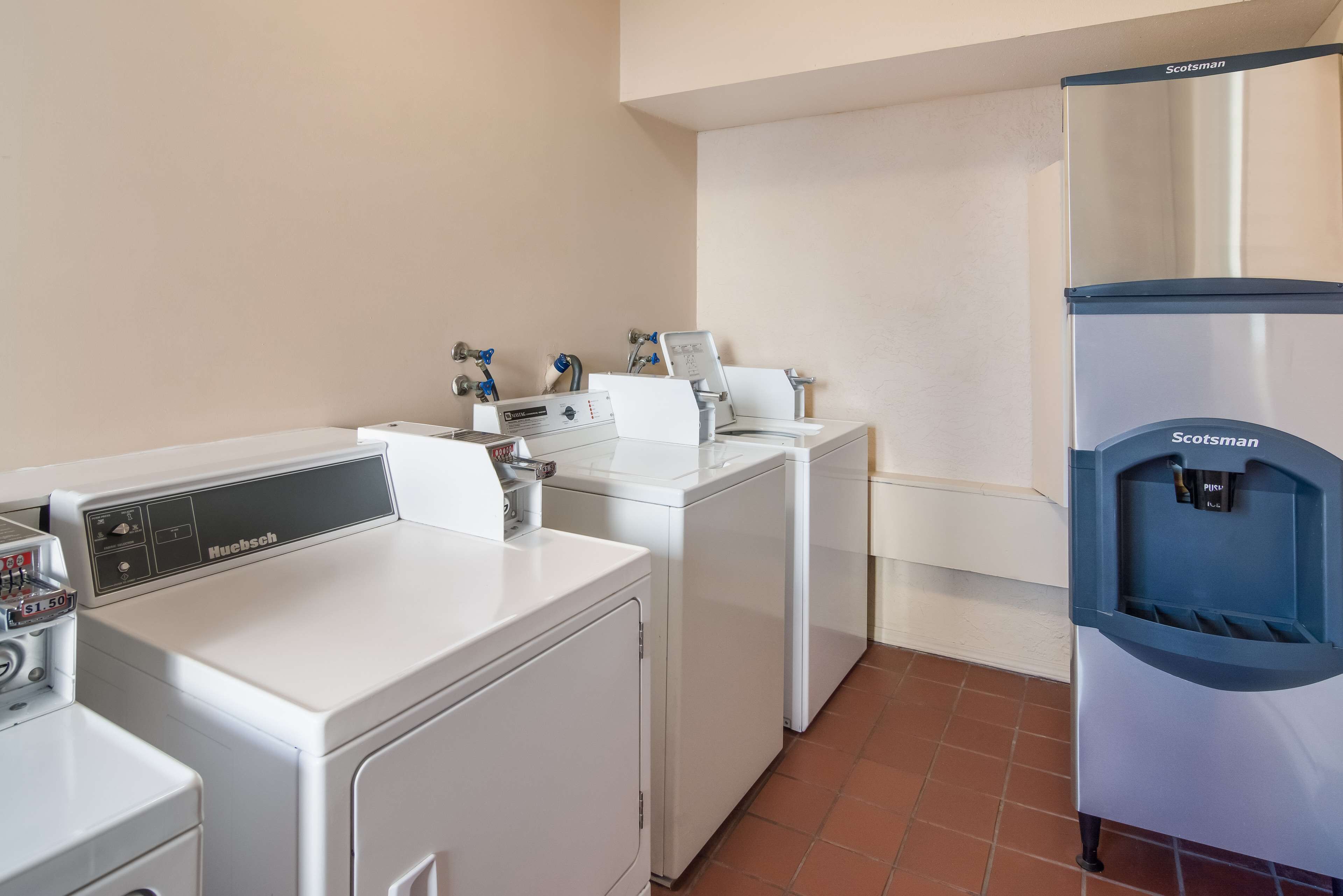 A laundry area with a Nubsch washer and dryer, a Scotsman water cooler, and a white wall.