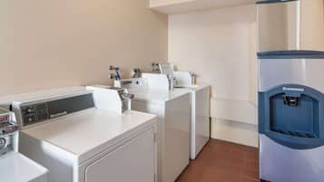 A laundry area with a Nubsch washer and dryer, a Scotsman water cooler, and a white wall.
