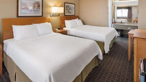 Ein Hotelzimmer mit zwei Betten, einem Badezimmer mit Spiegel und einem kleinen Schreibtisch.
