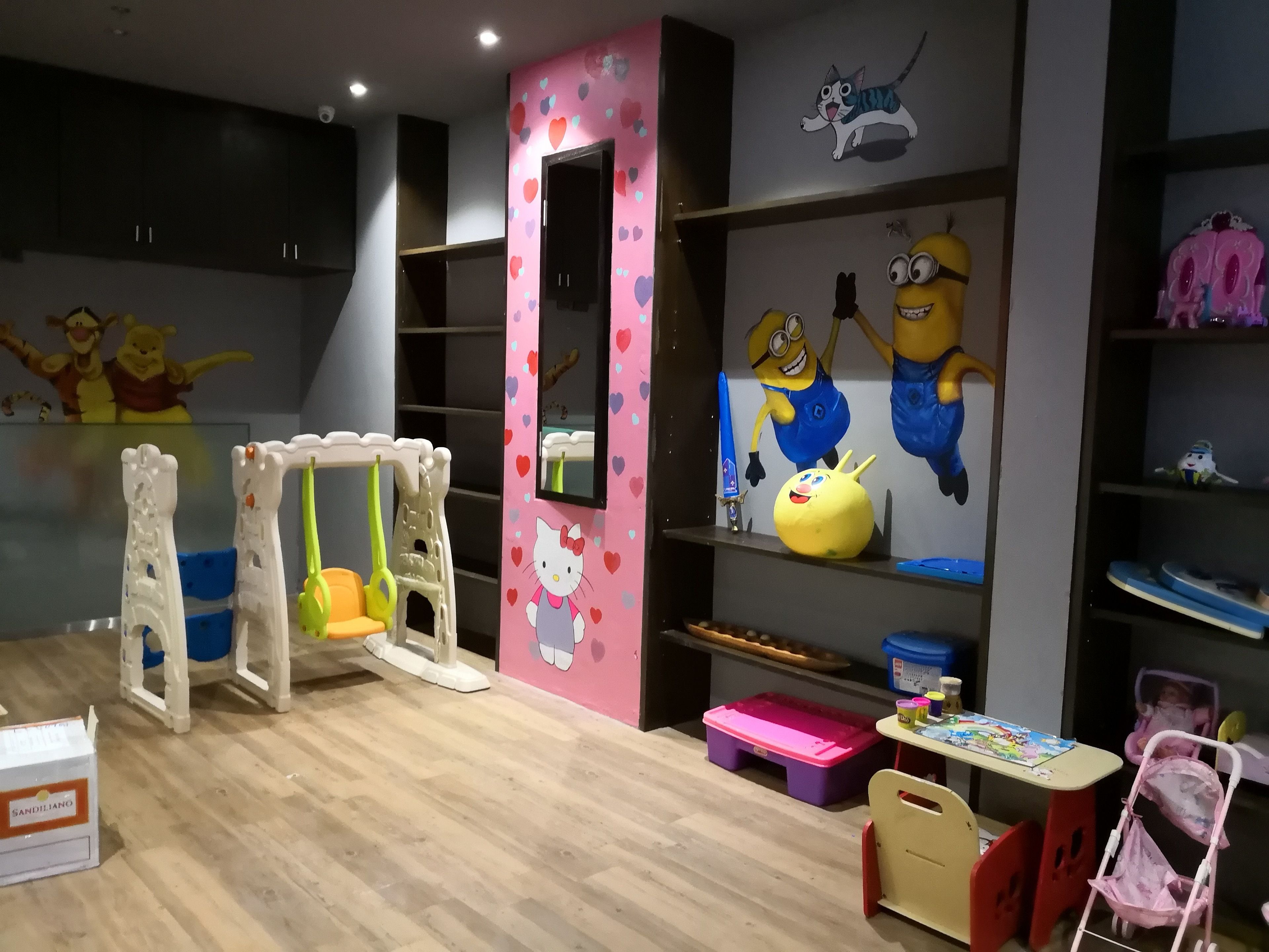 A children's play area with a swing set, a pink playpen, and Minion-themed decorations.