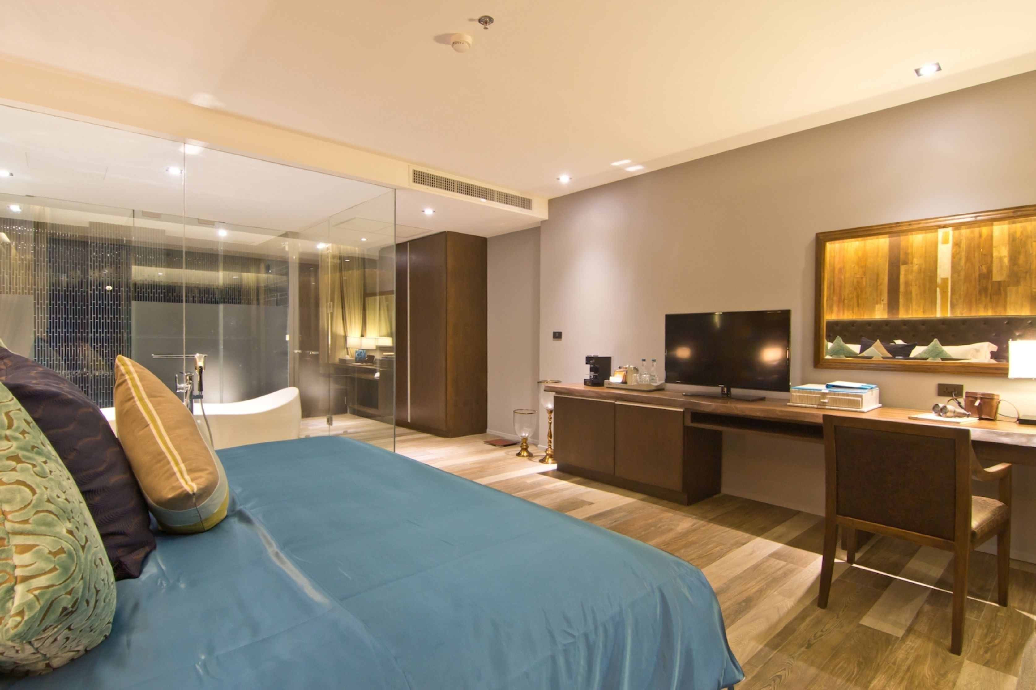 A modern hotel room with a large bed, a desk, and a TV.