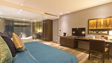 A modern hotel room with a large bed, a desk, and a TV.