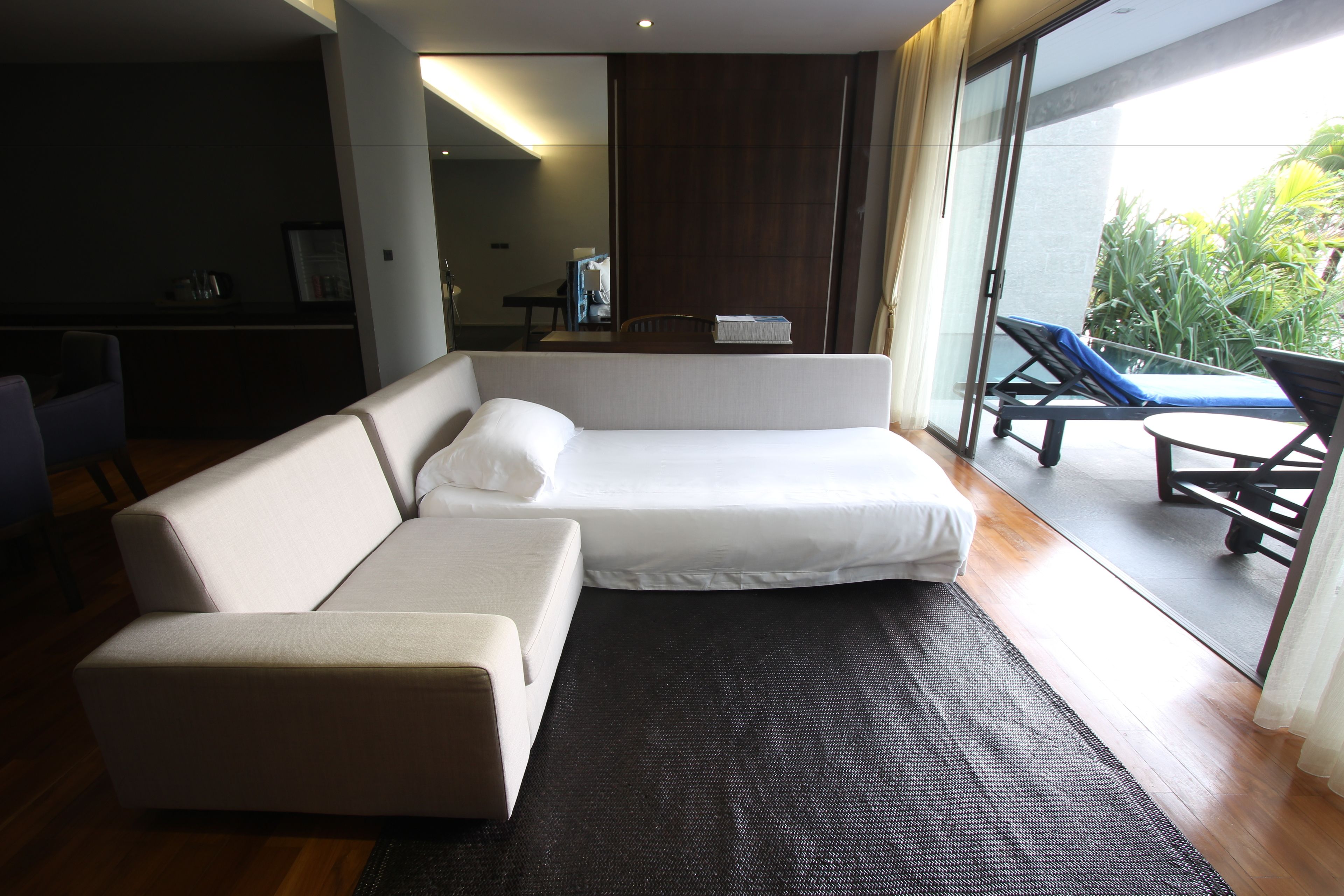A modern hotel room with a sofa, a small table, and a view of the outdoors.