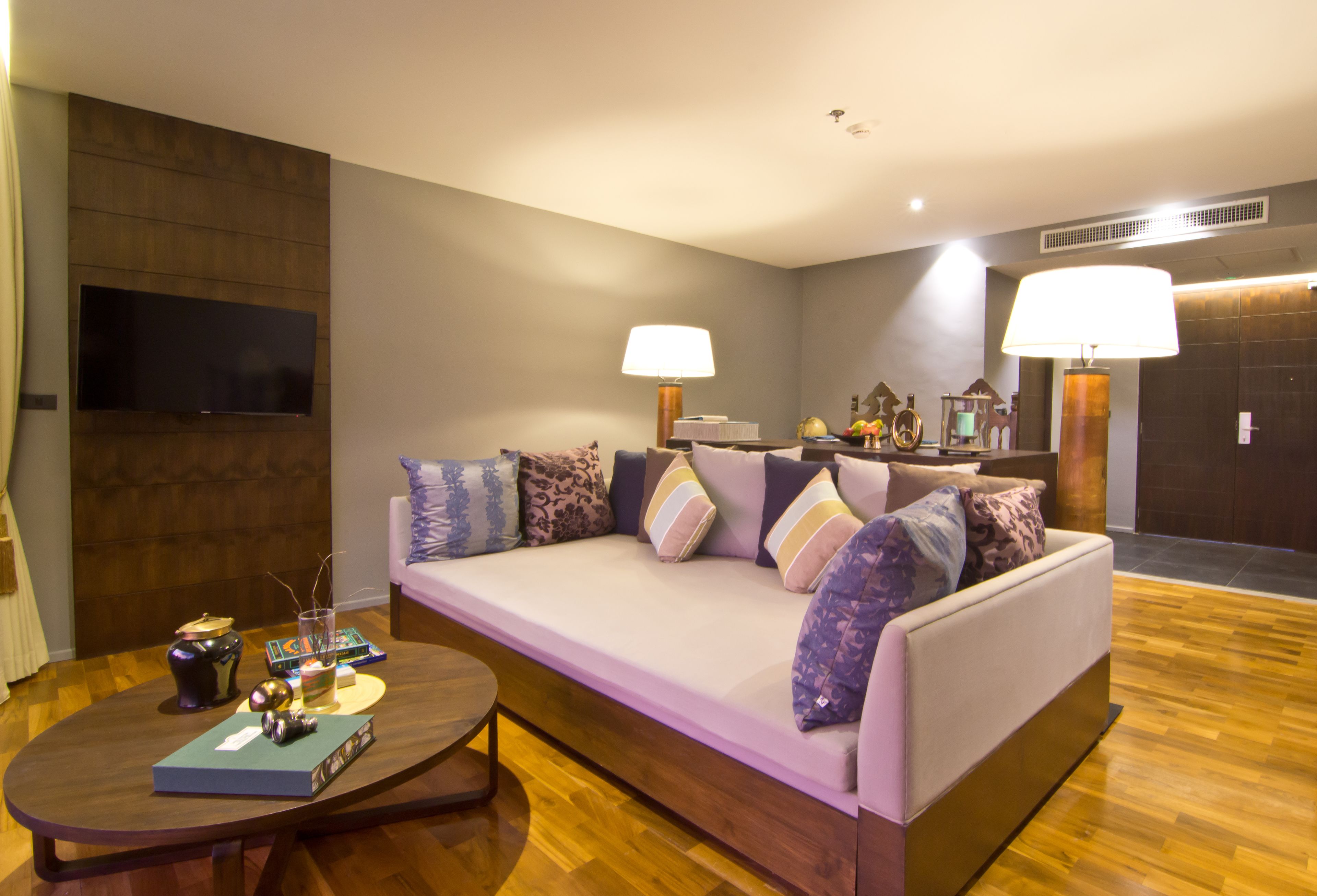 A modern living room with a sofa, two lamps, a flat-screen TV, and a coffee table.