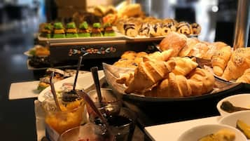 Una mesa de buffet con diversos pasteles, postres y salsas.