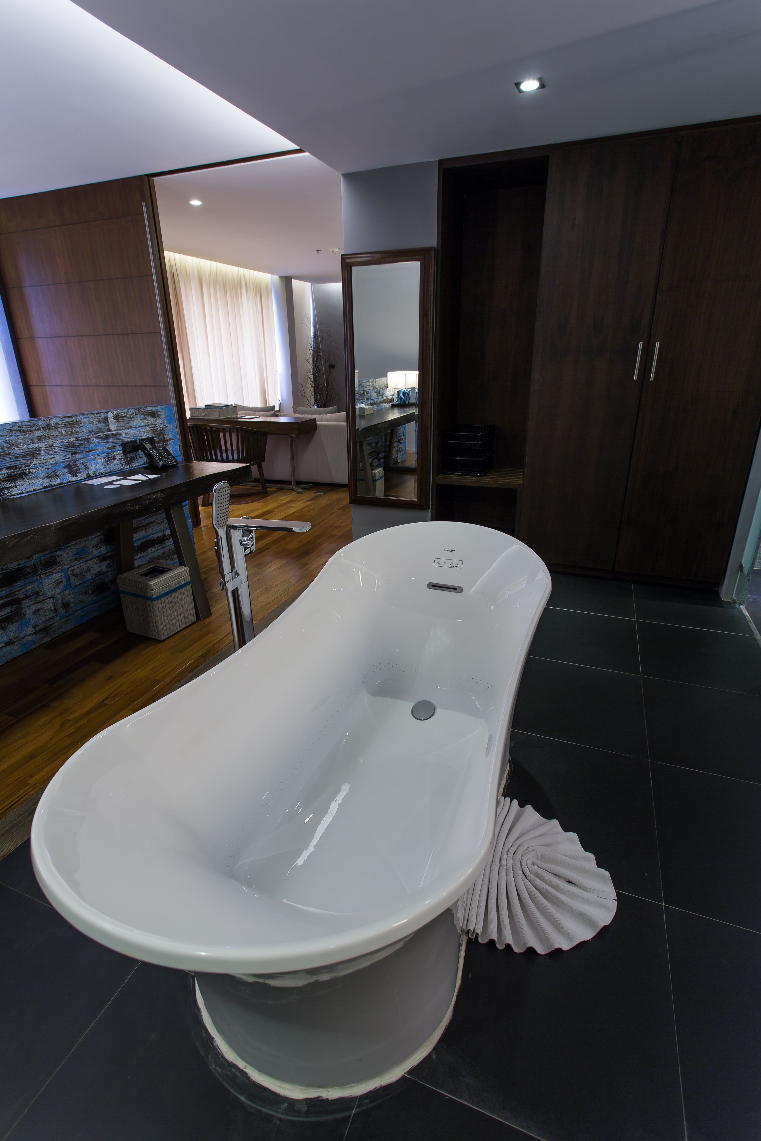 A modern bathroom with a freestanding bathtub, a wooden vanity, and a large mirror.