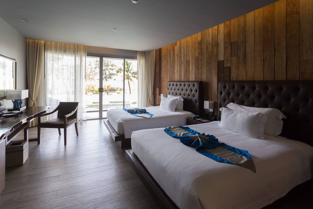 A hotel room with two beds, a desk, and a chair.