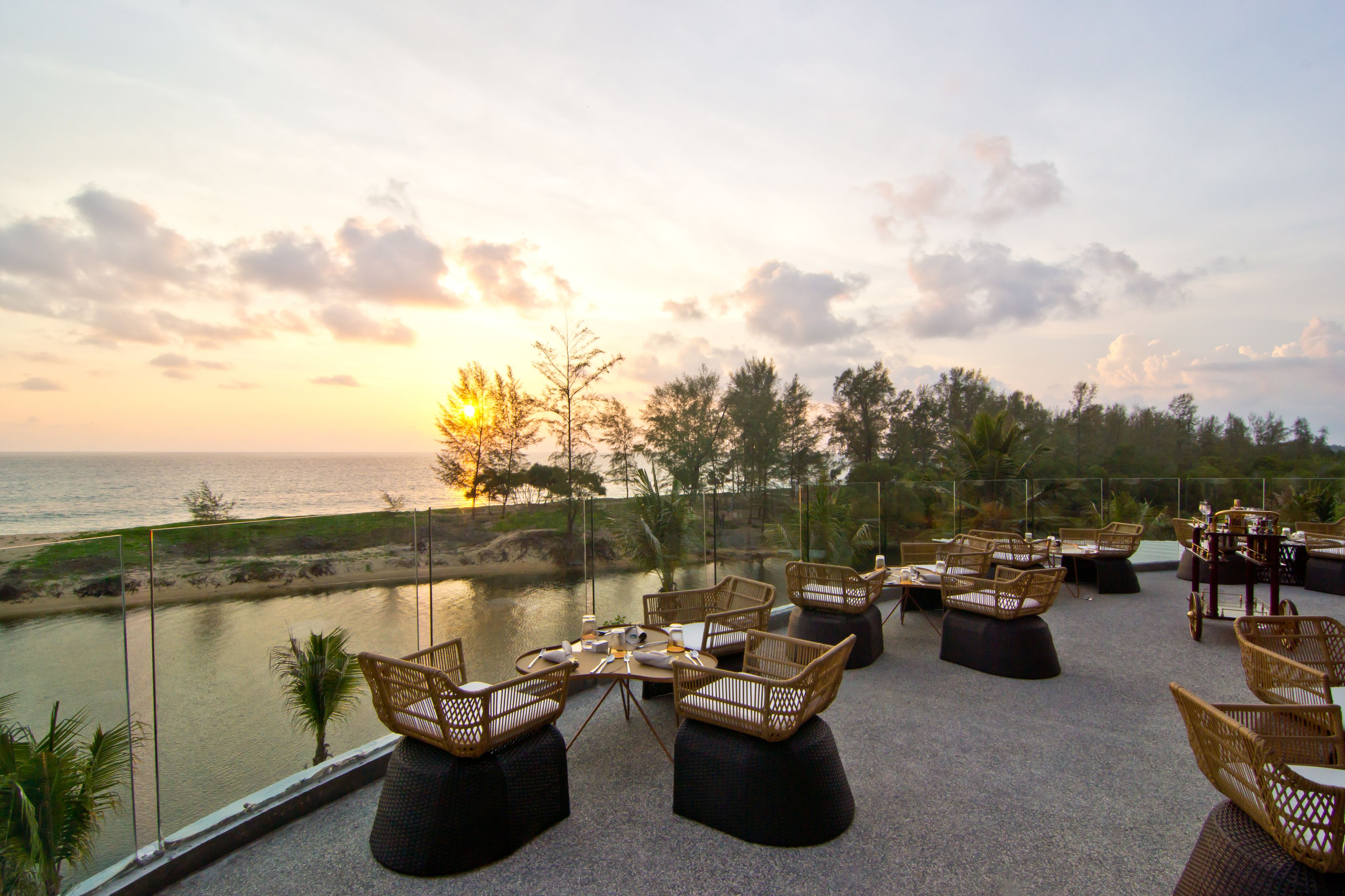 A terrace with wicker furniture, a view of the sea, and a clear sky.
