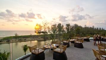 A terrace with wicker furniture, a view of the sea, and a clear sky.