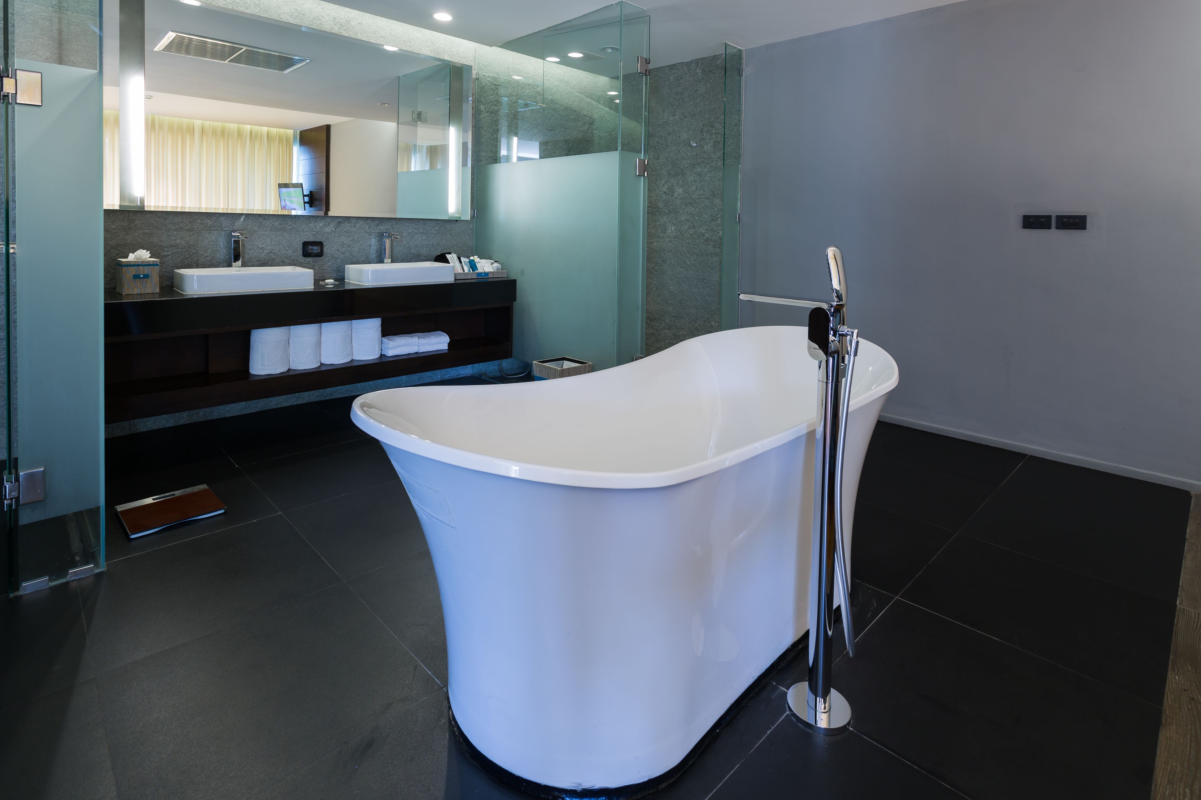 Une salle de bain moderne avec une baignoire sur pieds, deux vasques et un grand miroir.