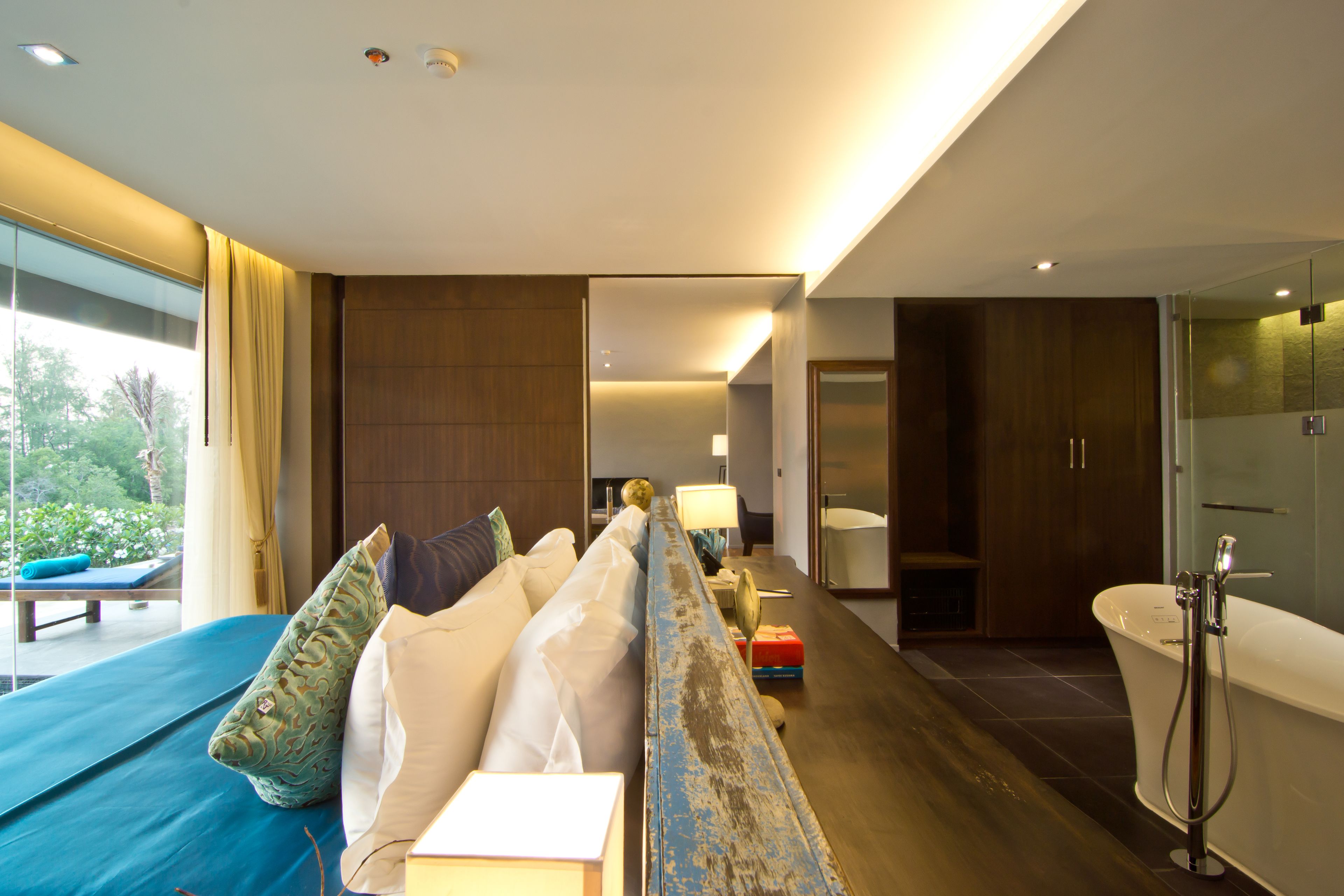 Ein modernes Hotelzimmer mit einem großen Bett, einer Sitzecke, einem Badezimmer mit Badewanne und Blick ins Freie.
