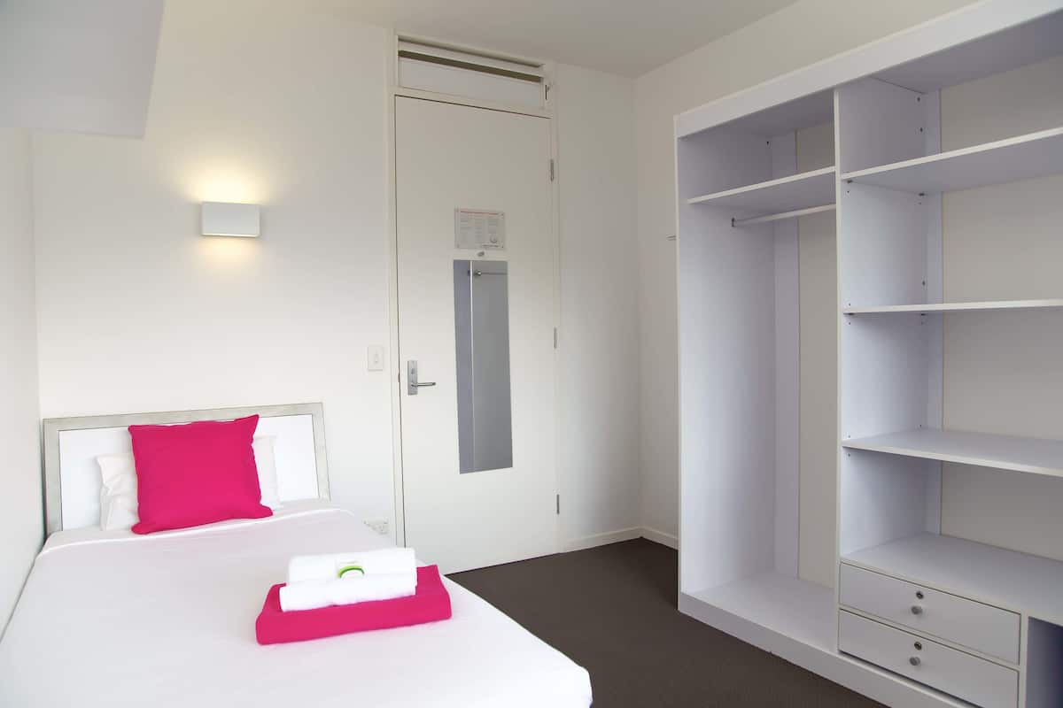 Quarto de hotel com cama, guarda-roupa e porta com aviso.