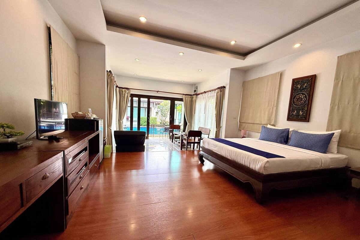 Una habitación de hotel moderna con una cama grande, un escritorio con una computadora y vistas a una piscina.
