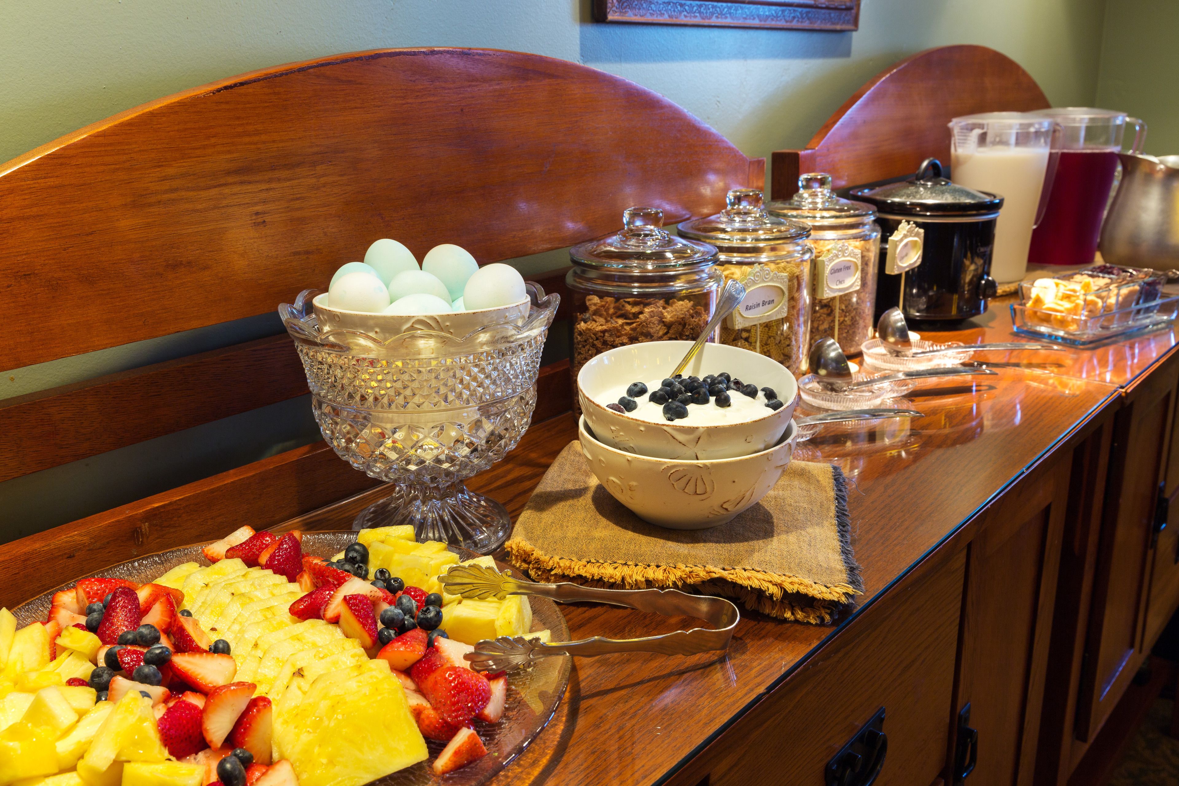 A breakfast buffet with various fruits, eggs, and beverages.