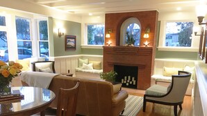 A cozy living room with a fireplace, a sofa, a dining table, and a chair. - 1906 Lodge (Coronado)