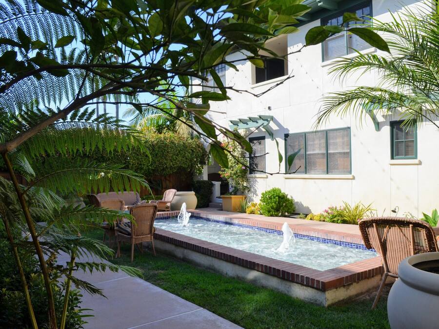 A backyard with a hot tub, patio furniture, and a white building in the background.