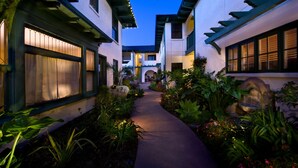 A narrow pathway flanked by buildings with large windows and a well-maintained garden. - 1906 Lodge (Coronado)