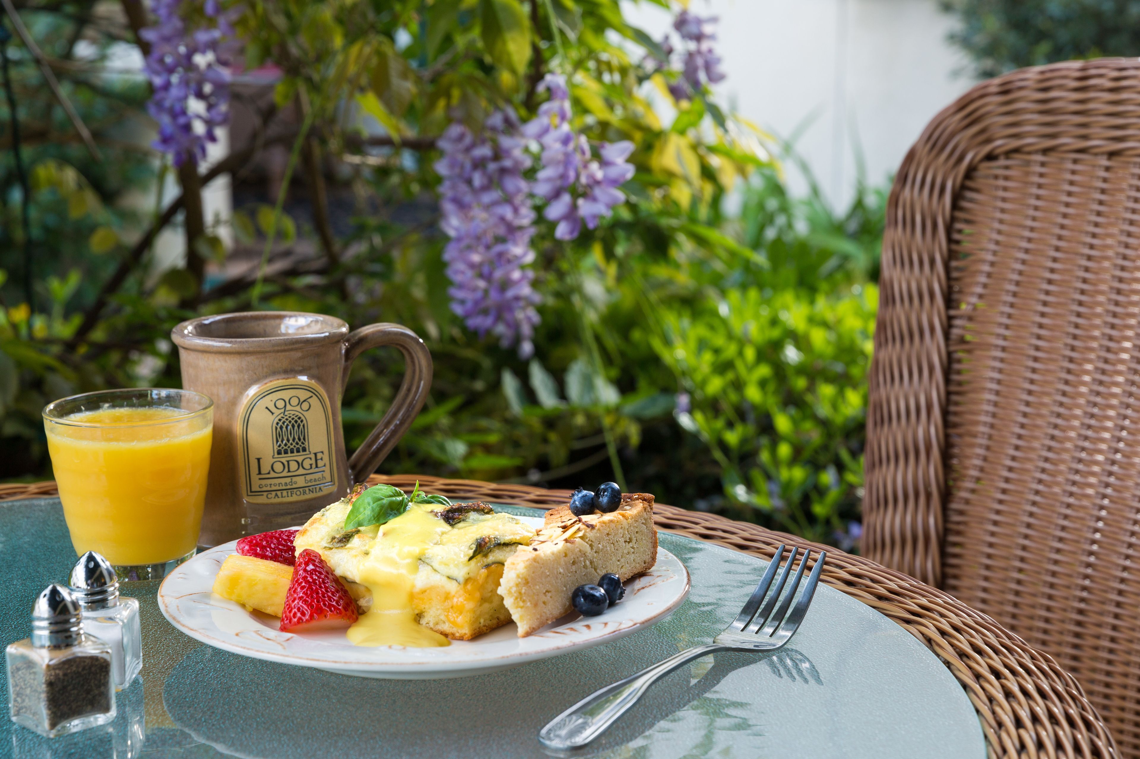 A breakfast setting with a plate of food, a mug, and a glass of orange juice on a table.