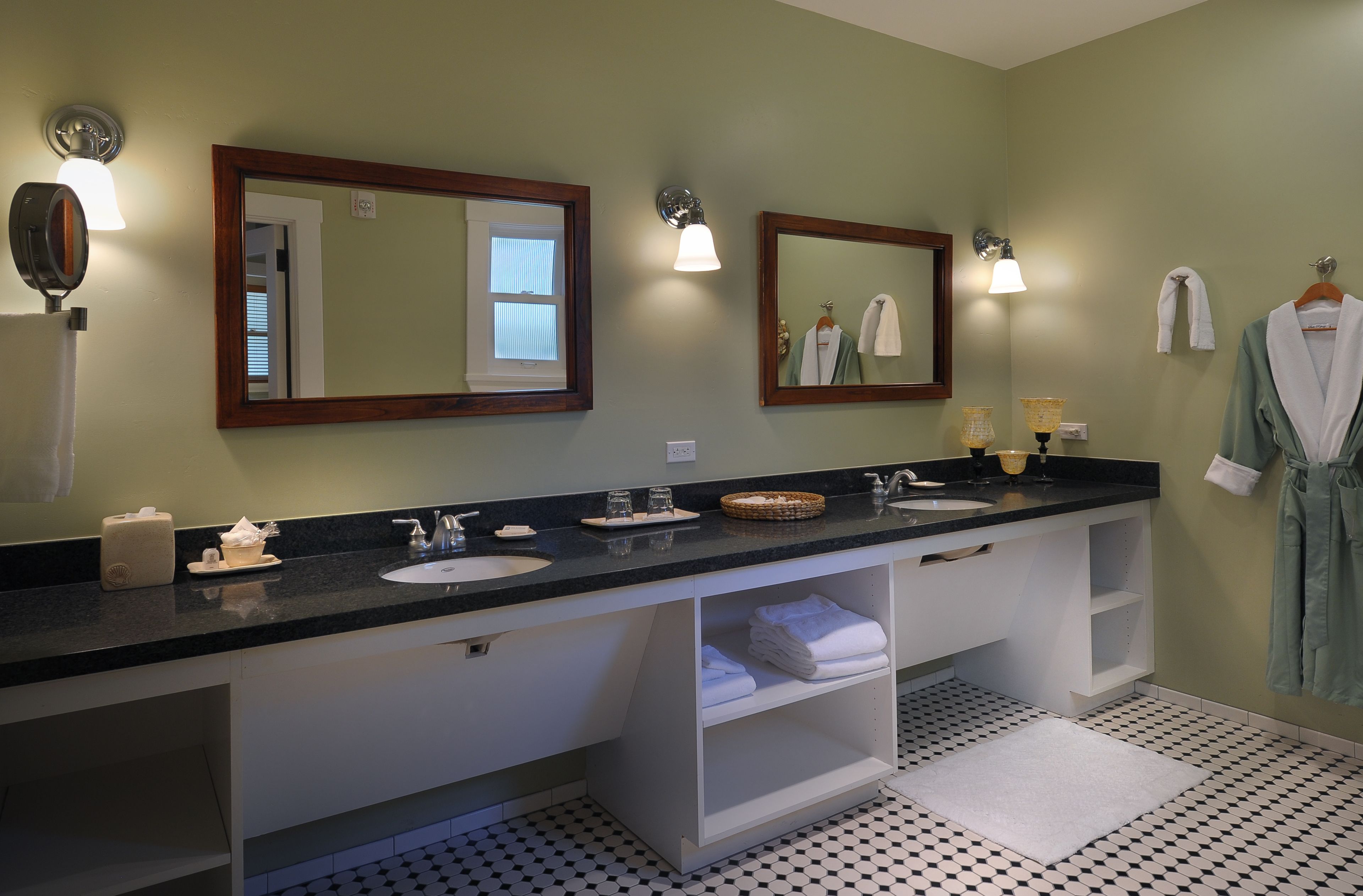 A bathroom with two sinks, a mirror, a towel rack, and a shelf with folded towels.