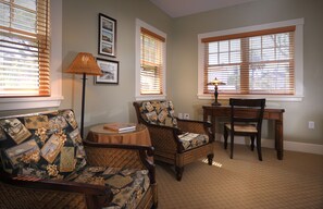 A living room with two patterned armchairs, a wooden table, and a floor lamp.