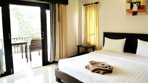 A hotel room with a large bed, a nightstand, a painting, and a balcony with a table and chairs. - Manita Resort (Koh Samui)