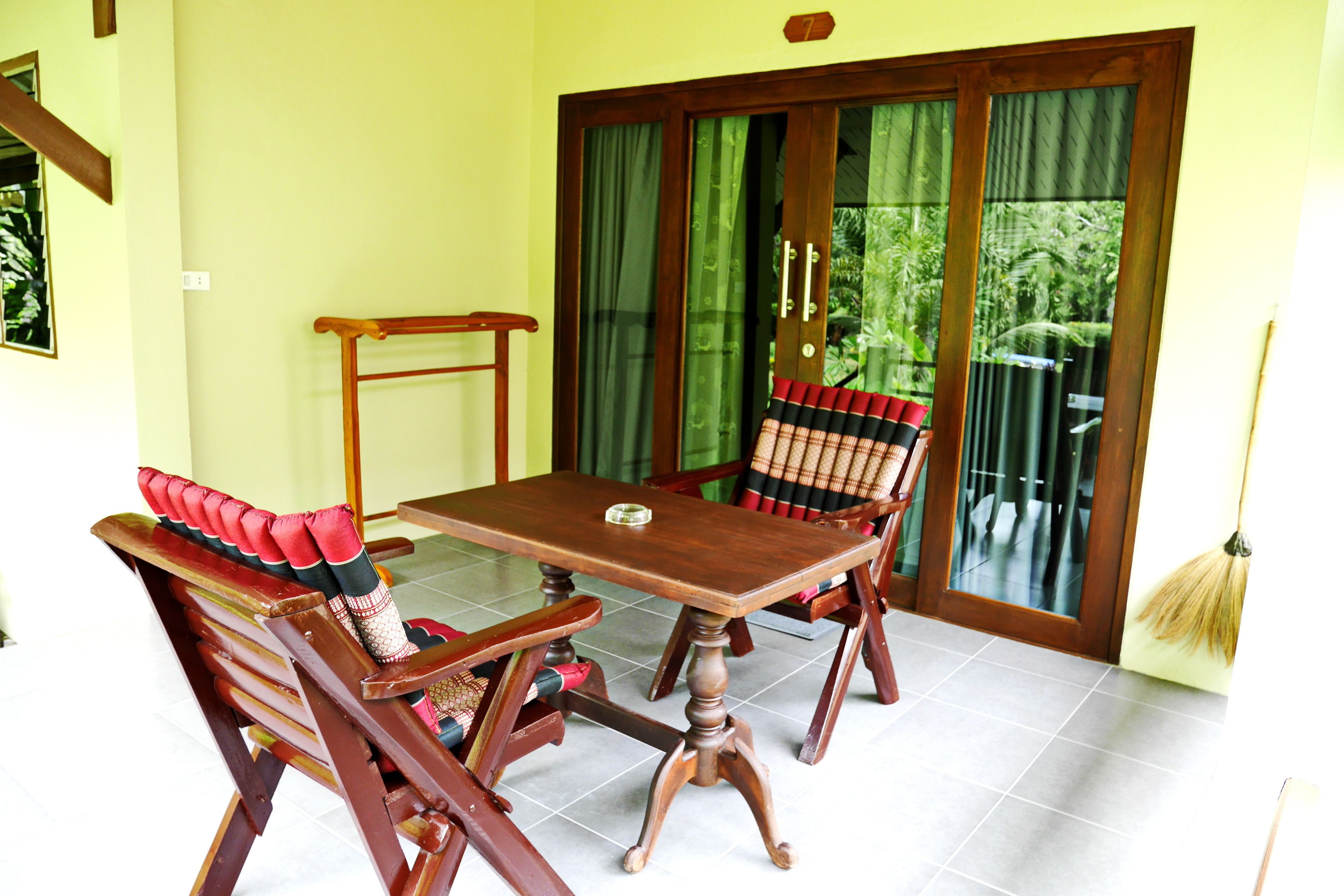 Un coin repas avec une table et des chaises en bois, un lambris en bois et une porte-fenêtre coulissante donnant sur un balcon.