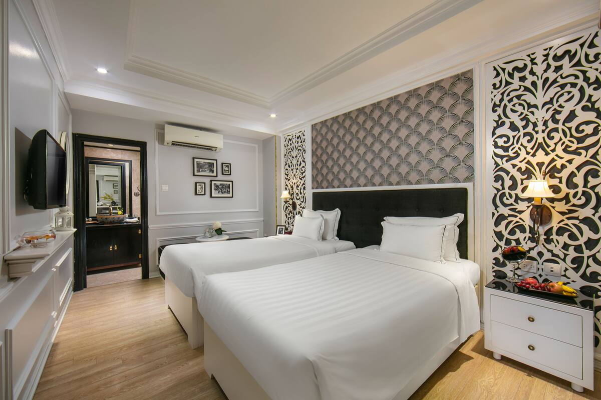 A hotel room with two beds, a dresser, a TV, and a decorative wall panel.