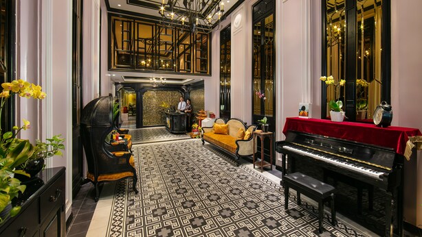 A grand lobby with a piano, a sofa, and a decorative mirror. - Lavender Central Hotel & Spa (Hanoi)