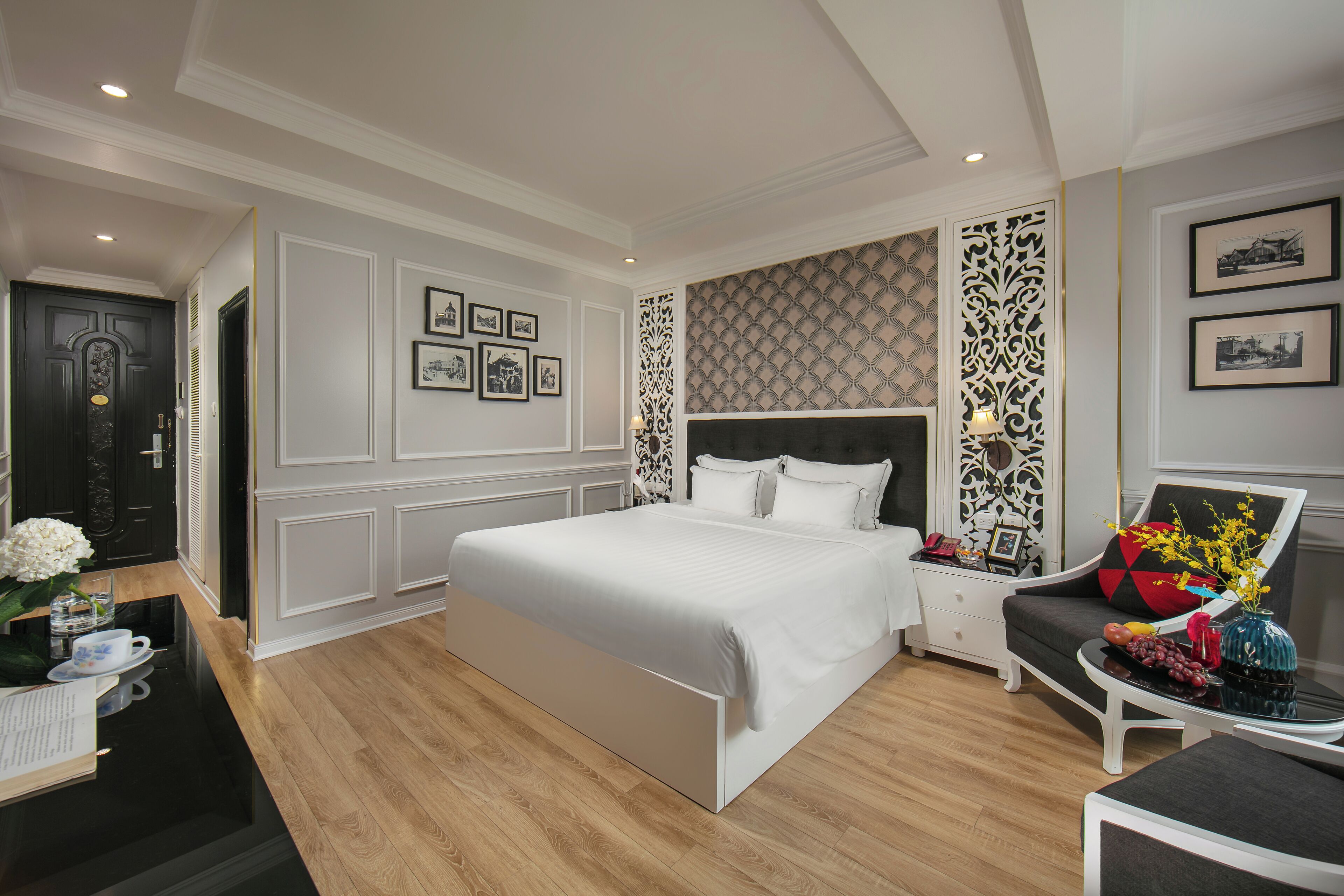 Una habitación de hotel moderna con una cama grande, una mesita de noche, una silla y un panel decorativo en la pared.