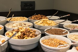 A buffet with various bowls of cereal and snacks. - Feeling Hotel Fontanella (Molveno)