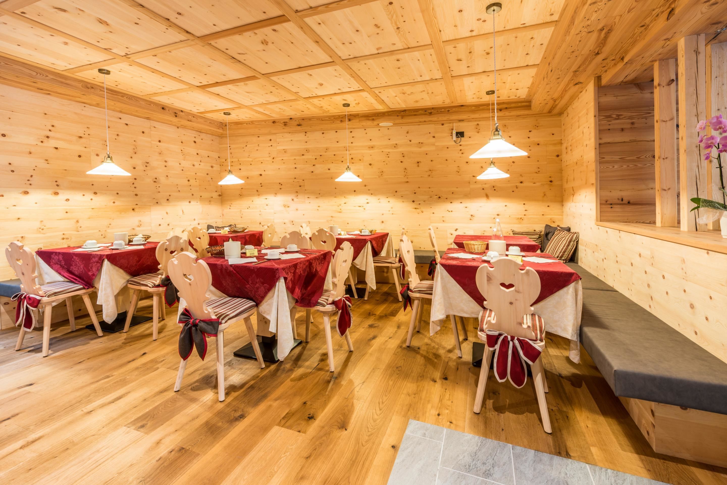 Une cabane en bois avec plusieurs tables et chaises, chacune recouverte d’une nappe rouge.