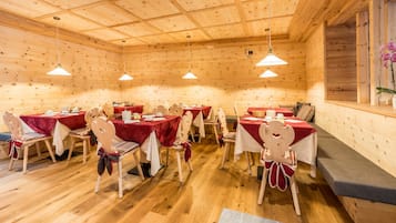 Une cabane en bois avec plusieurs tables et chaises, chacune recouverte d’une nappe rouge.