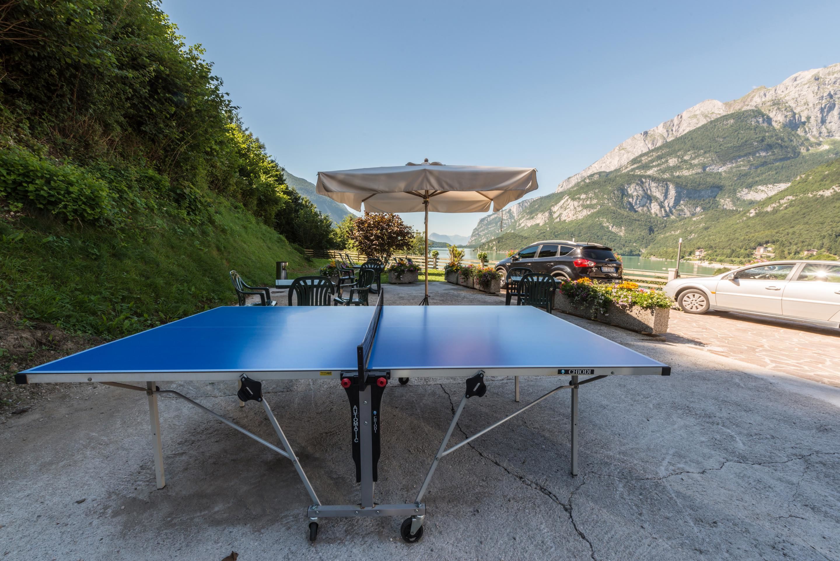 Ett bordtennisbord med ett parasoll, placerat utomhus med en bergskedja som bakgrund.