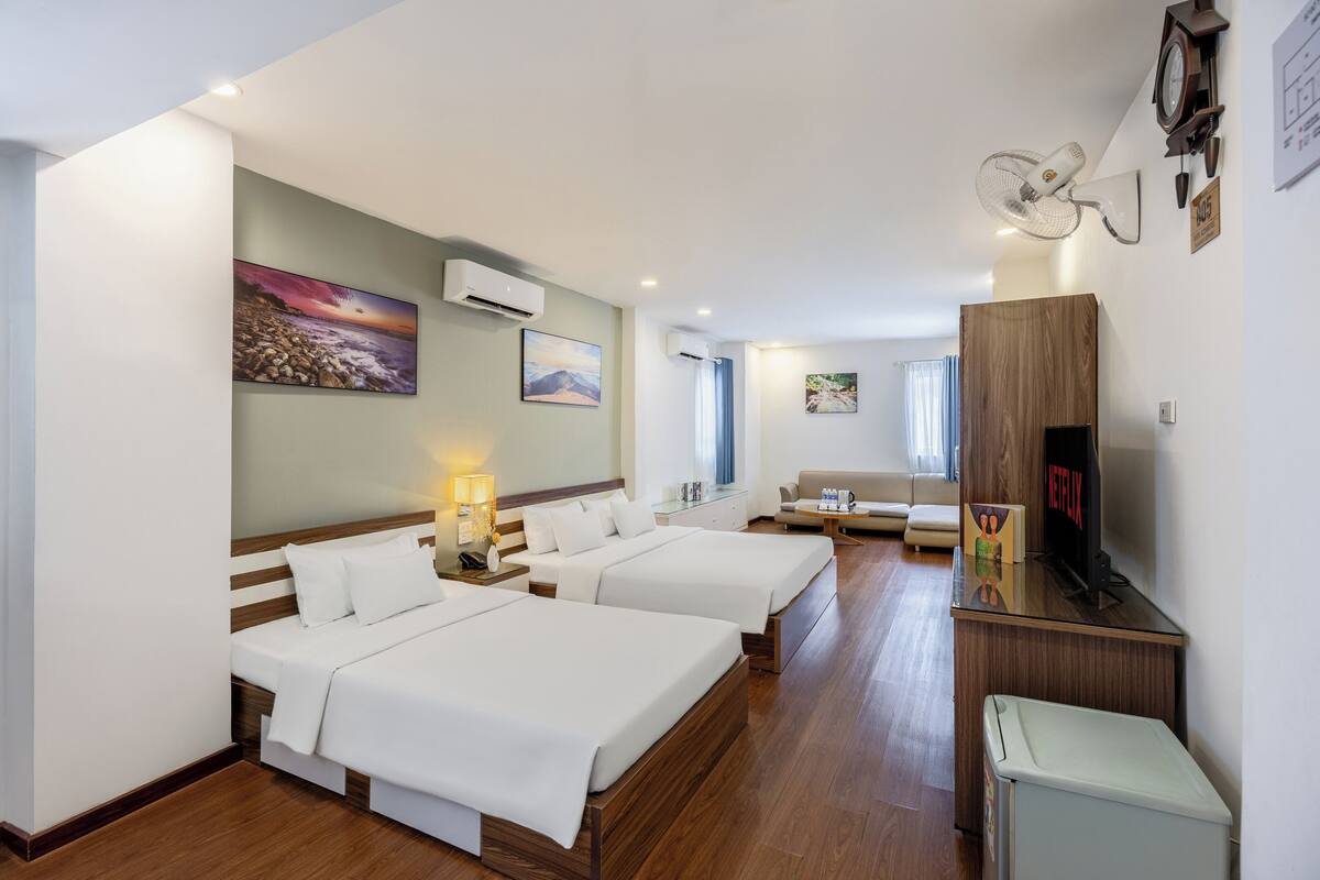 Ein Hotelzimmer mit zwei Betten, einem Schreibtisch mit Fernseher und einer Wanduhr.