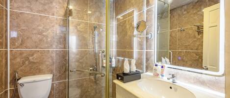 A modern bathroom with a glass-enclosed shower, a white toilet, and a large sink with a mirror.