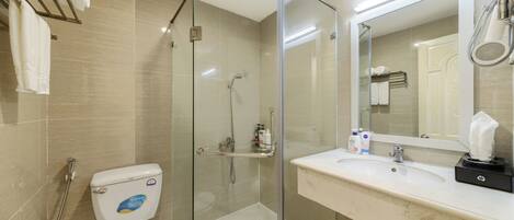A modern bathroom with a glass-enclosed shower, a white toilet, a marble sink, and a large mirror.