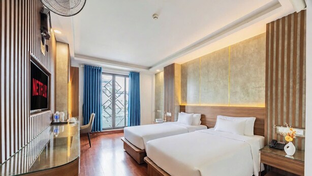 Une chambre d’hôtel avec deux lits, une télévision, un bureau et une vue sur la ville.