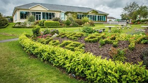 Une grande maison dotée d’un jardin bien entretenu, comprenant une pelouse, des parterres de fleurs et un espace patio.