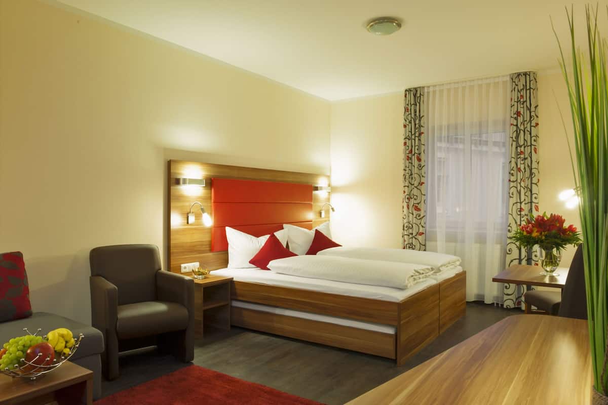 Ein Hotelzimmer mit einem Bett, einem Sessel, einem kleinen Tisch und einem Nachttisch.