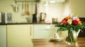 A kitchen with a wooden countertop, a vase of flowers, and a teapot on a small table. - BATU Apart Hotel (Munich)
