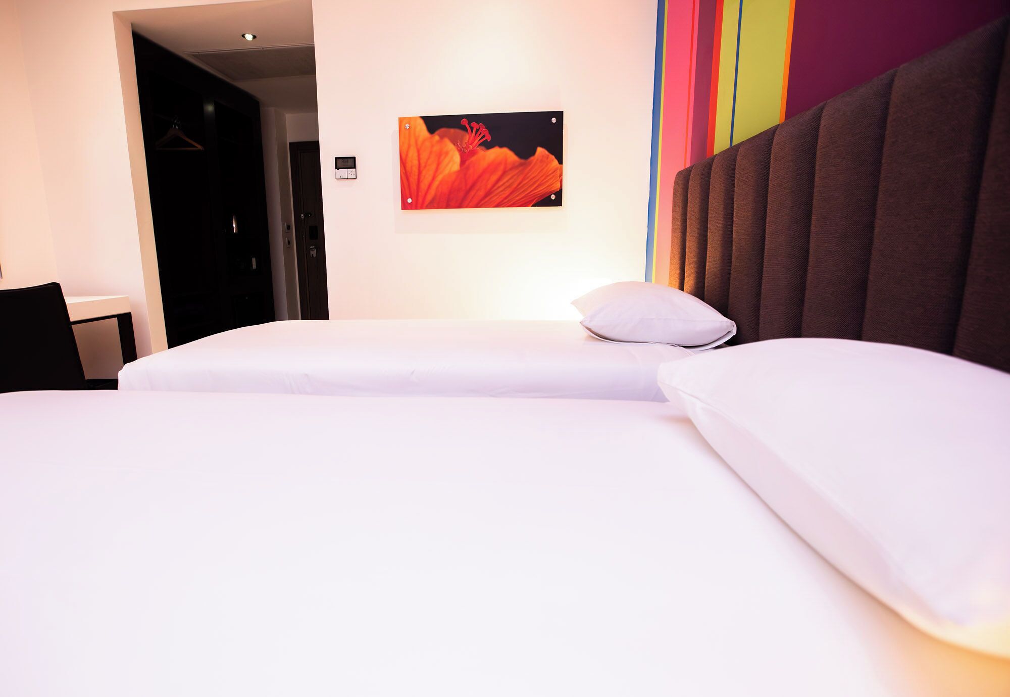A hotel room with a bed, a pillow, a wall-mounted picture, and a door.