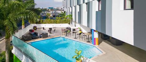 A rooftop pool area with lounge chairs, a small table, and a potted plant.