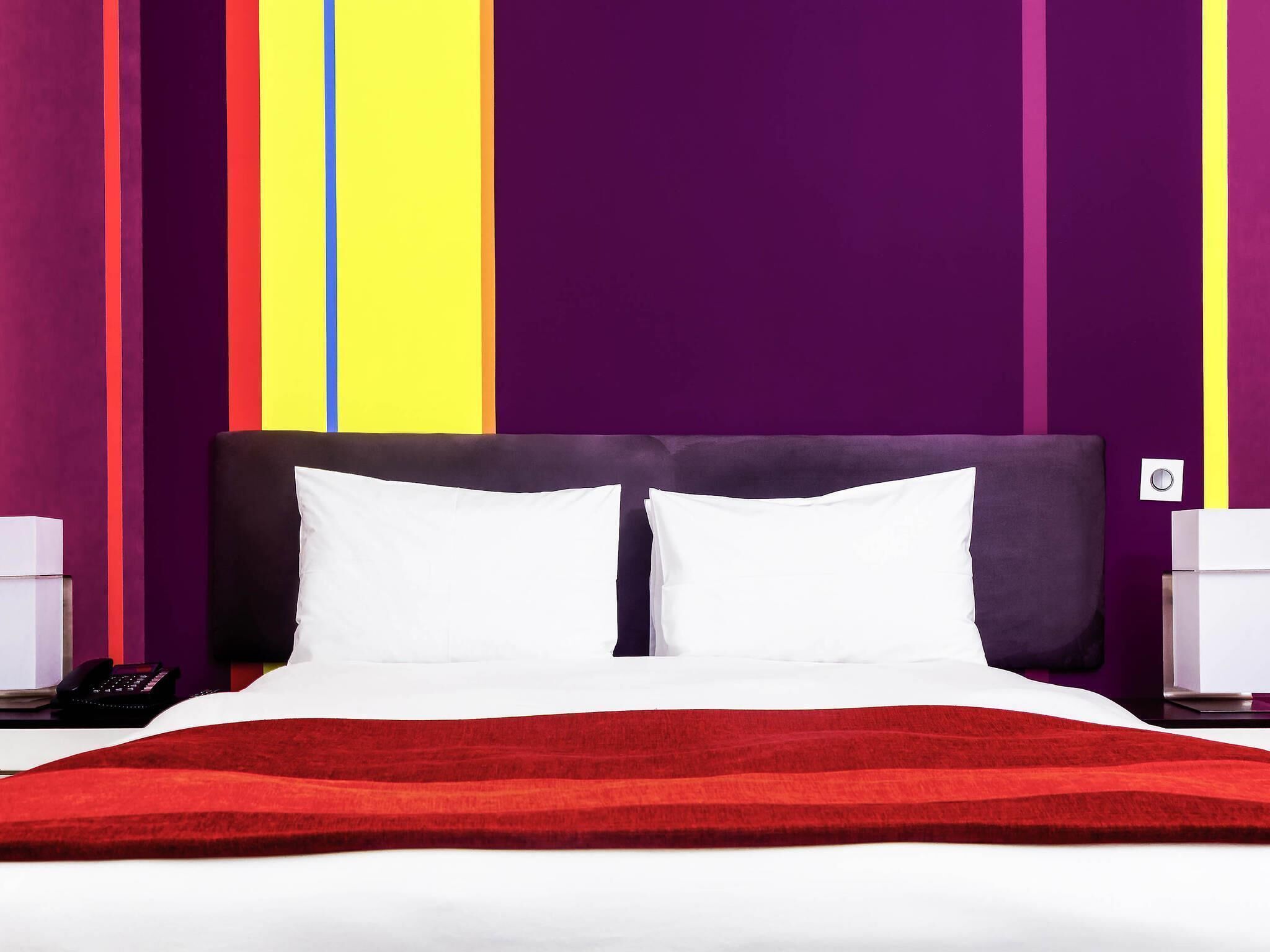Ein Bett mit weißer Bettwäsche, einer roten Decke und einem dunklen Kopfteil.