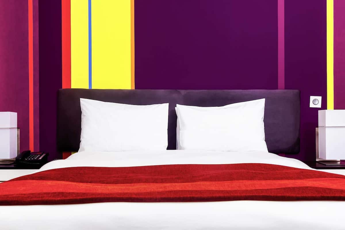 Ein Bett mit weißer Bettwäsche, einer roten Decke und einem dunklen Kopfteil.